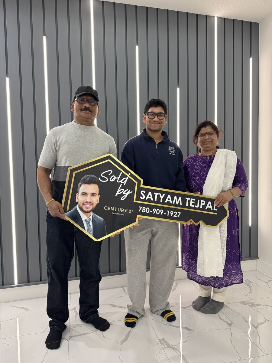 A family of three holding a Sold key sign inside their new home