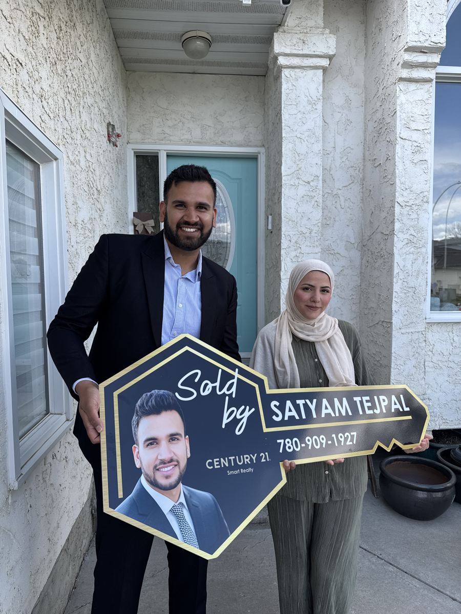 Satyam Tejpal and a client holding a Sold key sign at her front door
