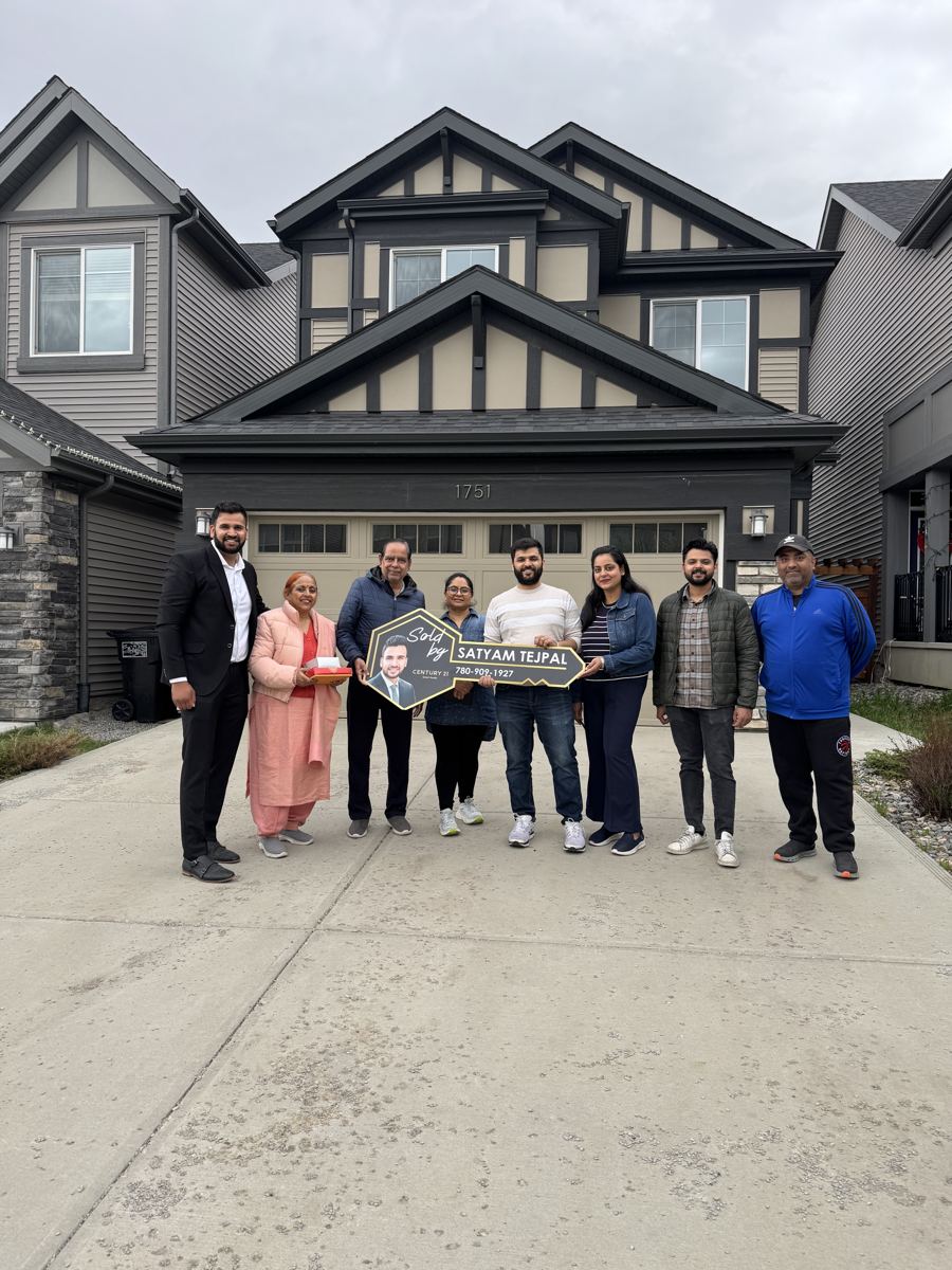 A large family with Satyam Tejpal in front of their new home, holding a Sold by Satyam Tejpal key sign